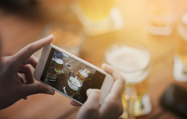 Gros plan des mains avec smartphone picturant bière — Photo