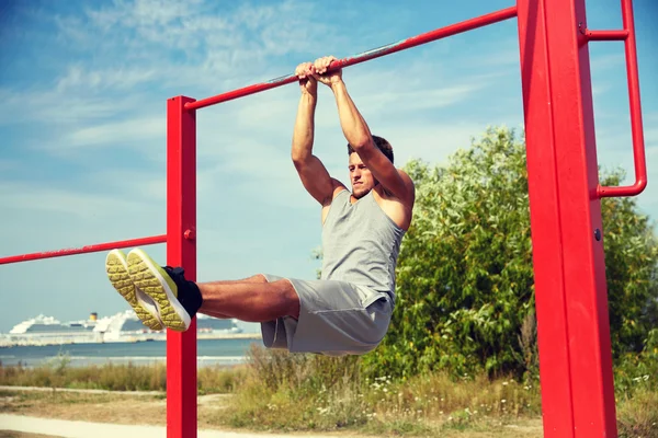 Joven ejercitándose en barra horizontal al aire libre —  Fotos de Stock