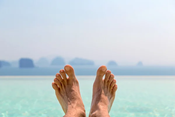 Крупный план мужских ног над морем и небом на пляже — стоковое фото