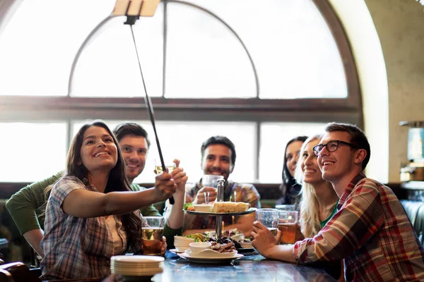 Gelukkige vrienden met selfie stok op bar of pub — Stockfoto