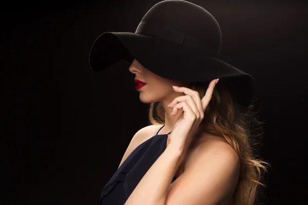 Belle femme en chapeau noir sur fond sombre — Photo