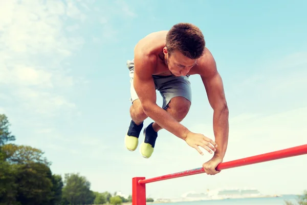 Jongeman die buiten op de horizontale balk traint — Stockfoto