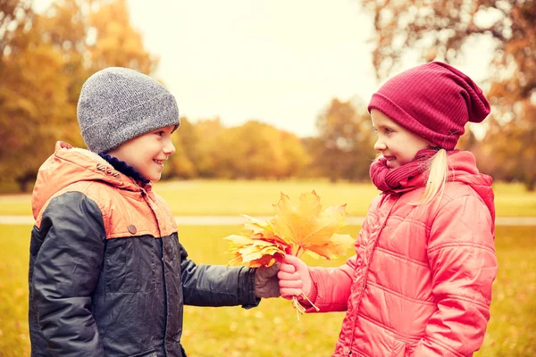 Petit garçon donnant feuilles d'érable d'automne à la fille — Photo