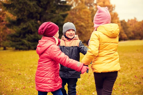 Дети держатся за руки и играют в осеннем парке — стоковое фото