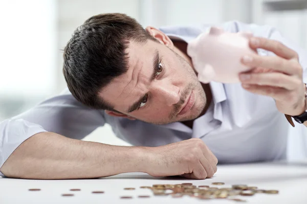 Businessman with piggy bank and coins at office Stock Photo