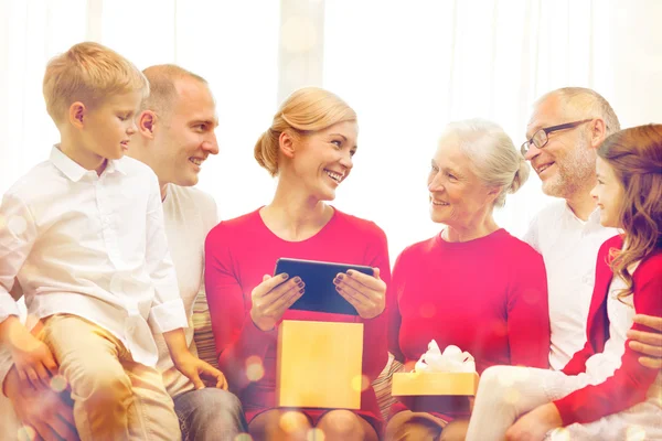 Família sorrindo com tablet pc e caixa de presente em casa — Fotografia de Stock
