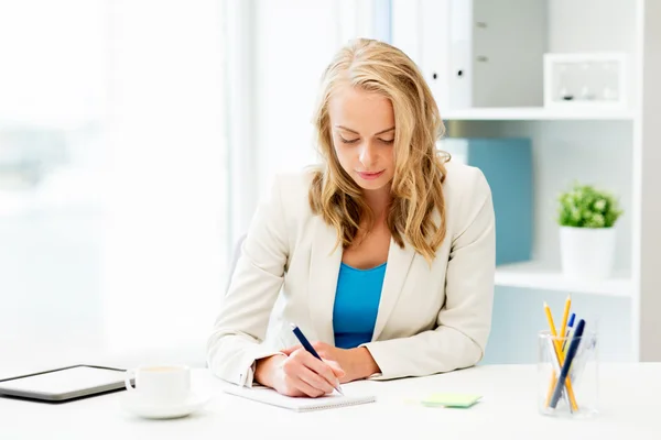 Business woman writing to notebook at office — стоковое фото