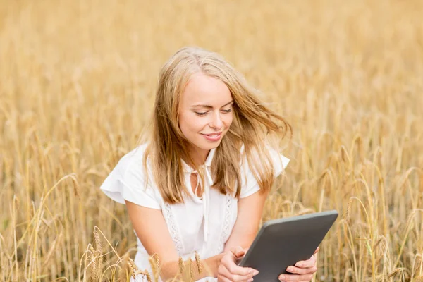 Gelukkig jong vrouw met tablet pc op graan veld — Stockfoto