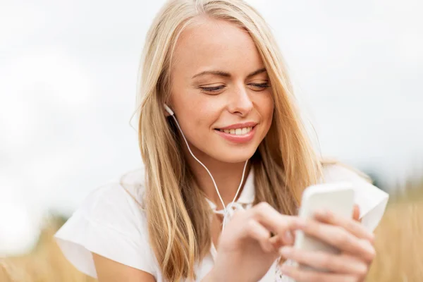 Gelukkige vrouw met smartphone en oortelefoons — Stockfoto