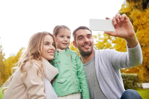 Счастливая семья делает селфи с помощью смартфона на улице — стоковое фото