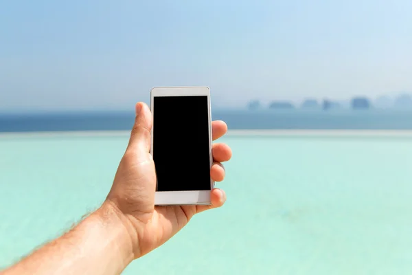 Nahaufnahme einer männlichen Hand, die ihr Smartphone am Strand hält — Stockfoto