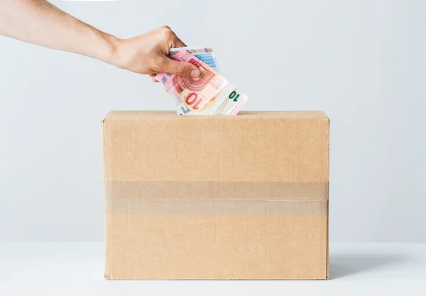 Hombre poniendo dinero en euros en la caja de donaciones — Foto de Stock