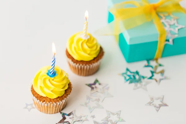 Birthday cupcakes with burning candles and present — Stock Photo, Image