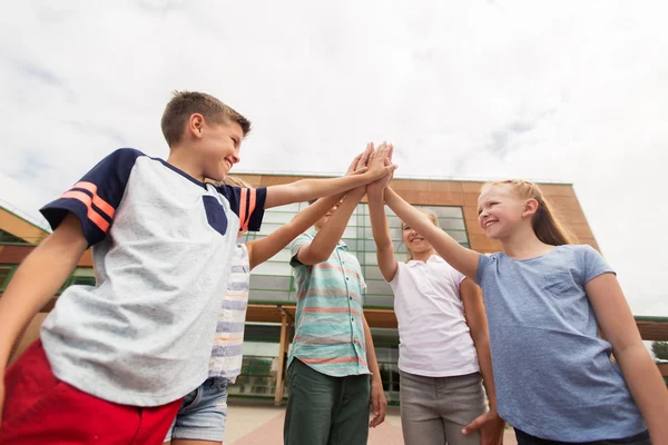 Grupo de niños haciendo high five en el patio de la escuela — Foto de Stock