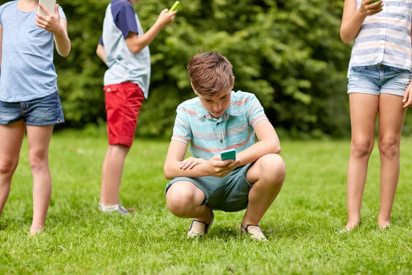 Anak-anak dengan smartphone bermain game di taman musim panas — Stok Foto