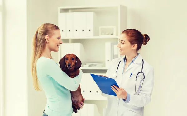 Mulher feliz com cão e médico na clínica veterinária — Fotografia de Stock