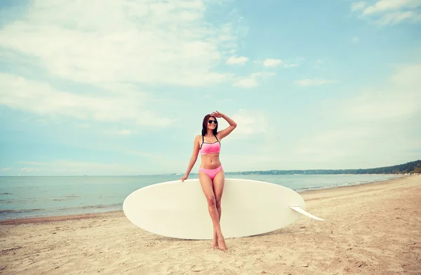 Улыбающаяся молодая женщина с доской для серфинга на пляже — стоковое фото