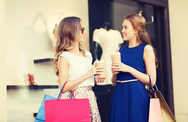 Jonge vrouwen met boodschappentassen en koffie bij shop — Stockfoto