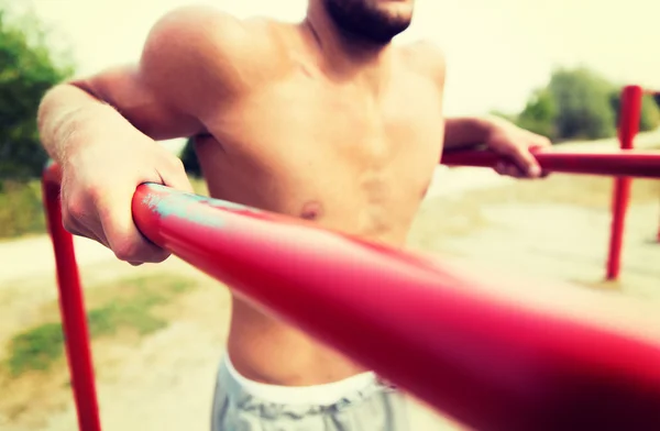 Young man exercising on parallel bars outdoors — Stock Photo, Image