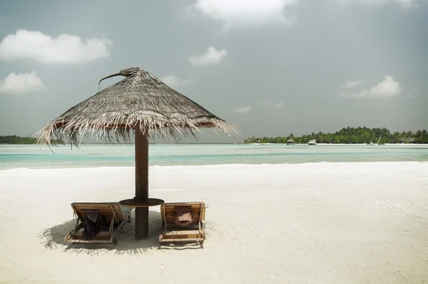 Palapa e espreguiçadeiras por mar na praia das maldivas — Fotografia de Stock