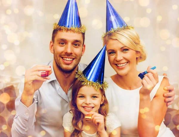 Sonriente familia en sombreros azules soplando cuernos favor — Foto de Stock