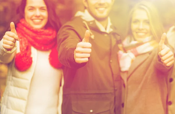 Happy friends showing thumbs up in autumn park — Stock Photo, Image