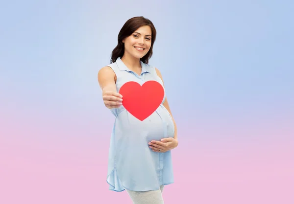 Glückliche schwangere Frau mit rotem Herz, das den Bauch berührt — Stockfoto