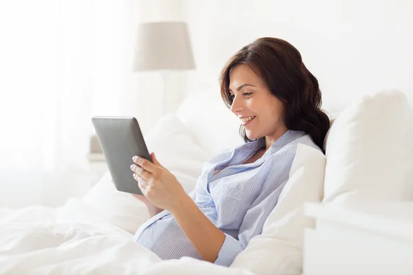 Mulher grávida feliz com tablet pc em casa — Fotografia de Stock
