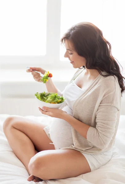 Feliz mujer embarazada comiendo ensalada en casa —  Fotos de Stock