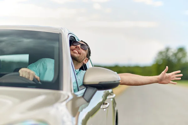 Lycklig man i nyanser kör bil och viftande hand — Stockfoto