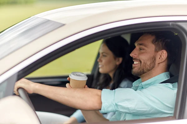 Happy man and woman driving in car with coffee — Stock Photo, Image