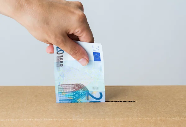 Hombre poniendo dinero en euros en la caja de donaciones —  Fotos de Stock