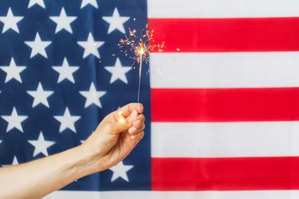 Close up de mão com sparkler sobre bandeira americana — Fotografia de Stock