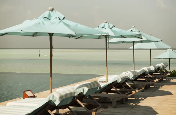 Sonnenschirm und Sonnenliegen am Strand der Malediven lizenzfreie Stockfotos