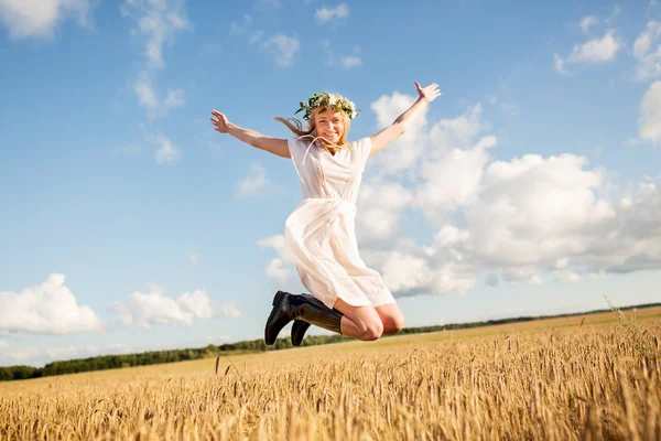 Счастливая женщина в венке прыгает на зерновом поле — стоковое фото
