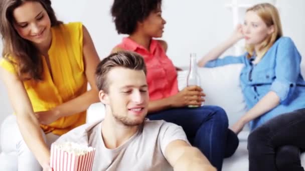 Друзья с попкорном и пивом смотрят телевизор дома — стоковое видео
