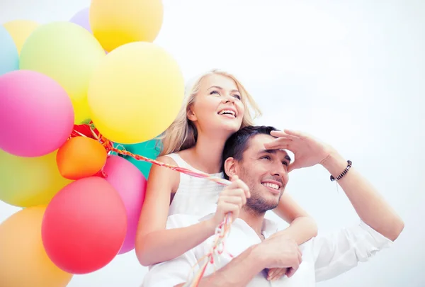 Casal com balões coloridos à beira-mar — Fotografia de Stock