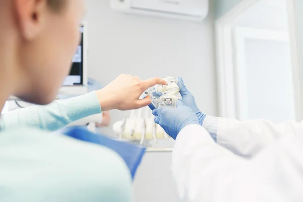 Close up of dentist with teeth model and patient — 스톡 사진