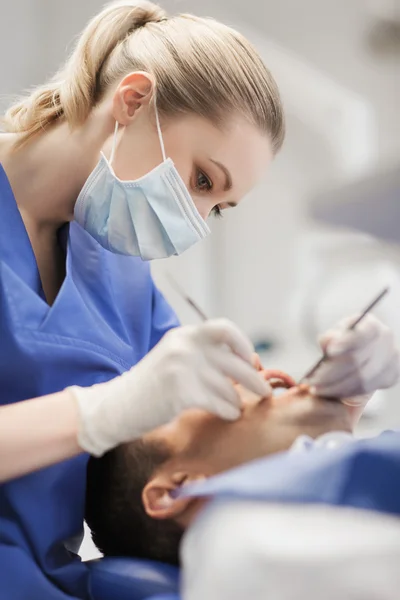 Kvinnliga tandläkare kontrollera upp manliga patientens tänder — Stockfoto