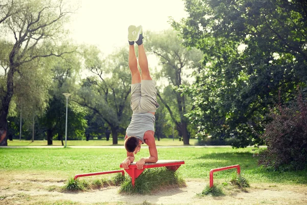 Jonge man uit te oefenen op bankje in park zomer — Stockfoto