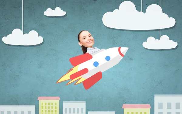 Business woman flying on rocket above cartoon city — стоковое фото