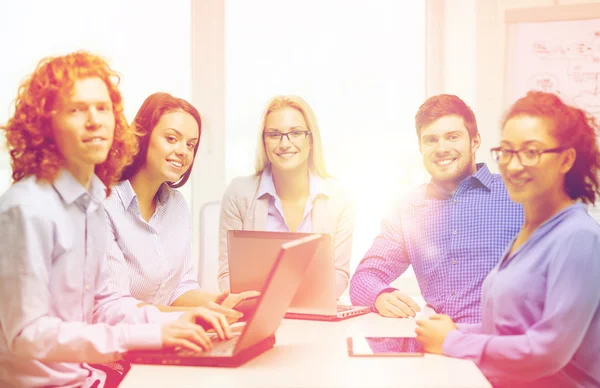 Equipo sonriente con computadoras portátiles y de mesa PC —  Fotos de Stock