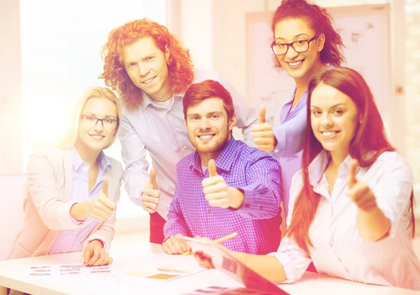 Equipe criativa com papéis mostrando polegares para cima — Fotografia de Stock