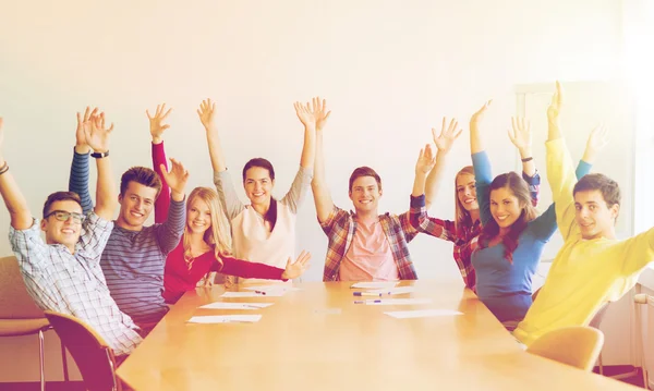 Group of smiling students raising hands in office — Stock Photo, Image