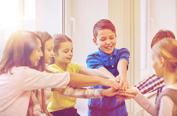 Grupo de niños sonriendo de la escuela poniendo las manos en la parte superior — Foto de Stock