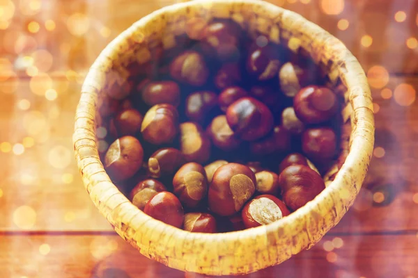 Close up of chestnuts in basket on wooden table — Stock Photo, Image