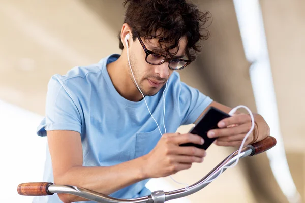 Adam akıllı telefon ve kulaklık üzerinde bisiklet — Stok fotoğraf