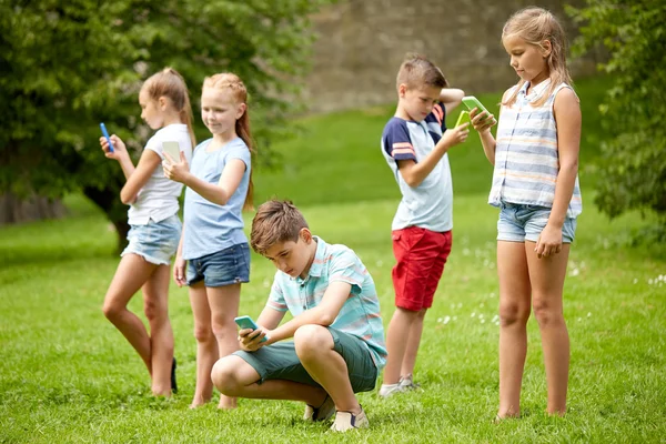 Anak-anak dengan smartphone bermain game di taman musim panas — Stok Foto