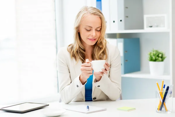 Šťastná podnikatelka pije kávu v kanceláři — Stock fotografie