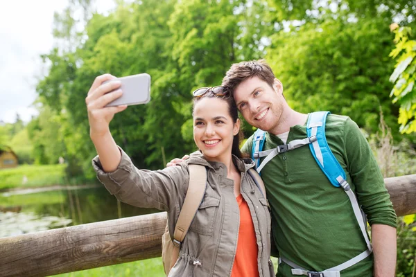 Para z plecakami biorąc selfie przez smartfona — Zdjęcie stockowe